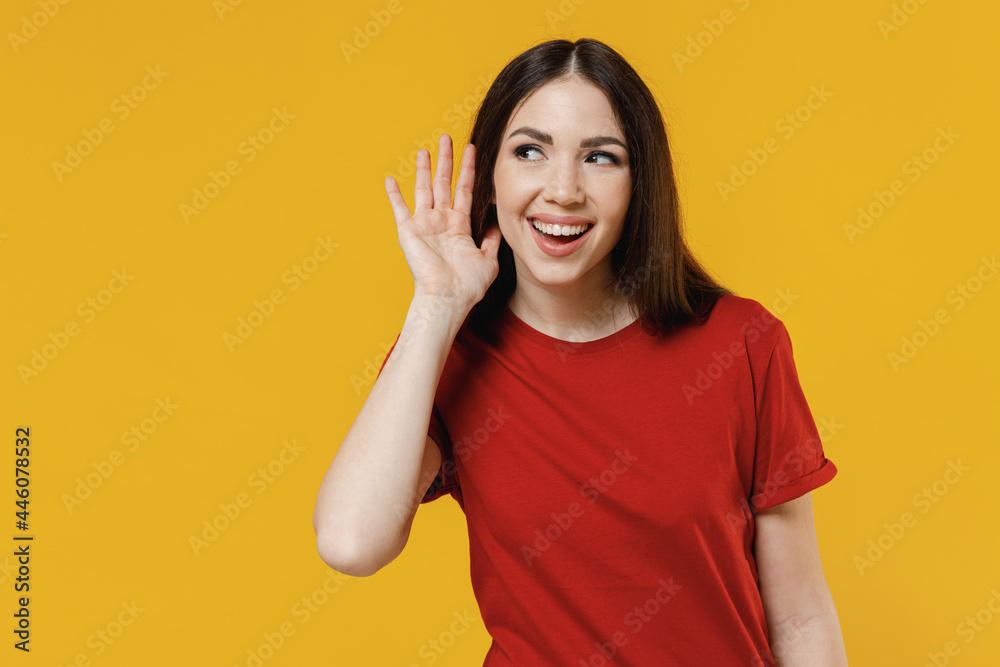 Curious nosy beautiful fun young brunette woman 20s wear basic red t-shirt try to hear you overhear listening intently isolated on yellow background studio portrait. People emotions lifestyle concept Curious nosy beautiful fun young brunette woman 20s wear basic red t-shirt try to hear you overhear listening intently isolated on yellow background studio portrait. People emotions lifestyle concept