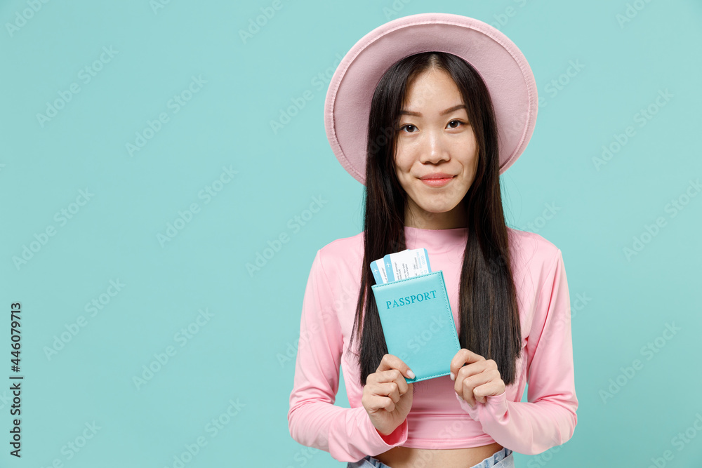 Traveler tourist asian woman in pink casual clothes hat hold passport boarding tickets isolated on pastel blue color background studio. Passenger travel abroad on weekends getaway Air flight concept Traveler tourist asian woman in pink casual clothes hat hold passport boarding tickets isolated on pastel blue color background studio. Passenger travel abroad on weekends getaway Air flight concept