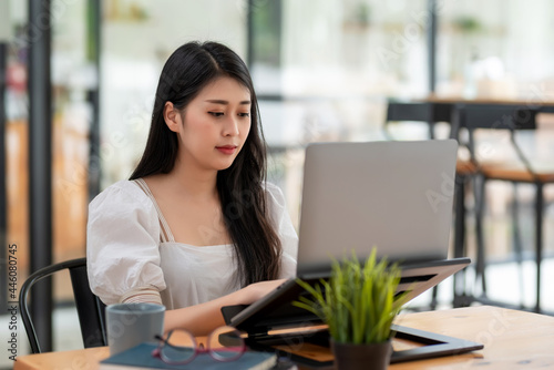Image of young Asian businesswoman sitting using laptop computer at the office.