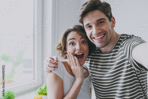 Close up young happy surpise couple two woman man 20s in casual tshirt clothes hug spend time together do selfie by mobile cell phone cook food in light kitchen at home Healthy diet lifestyle concept photo