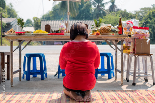 Tableau sur toile Asian woman red shirt sitting and praying to ancestor with meal,dessert and beve