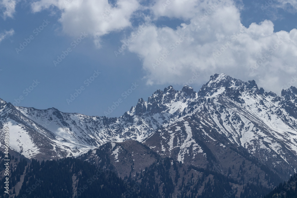 A view of the snowy peaks of the mountains, and behind them white clouds