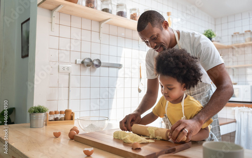 African American Father and son baking at home together. Child enjoying helping Dad. Brazilian family in the kitchen. photo