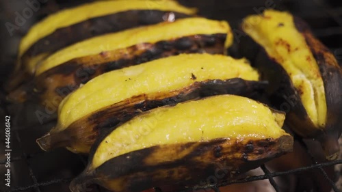 Grilled peeled banana on a traditional charcoal stove with some smoke. slow motion. tropical food. thai food. sweet dessert banana.