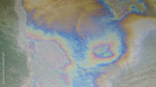 Aerial top down view to the sea surface with the rainbow-colored oil spill pattern