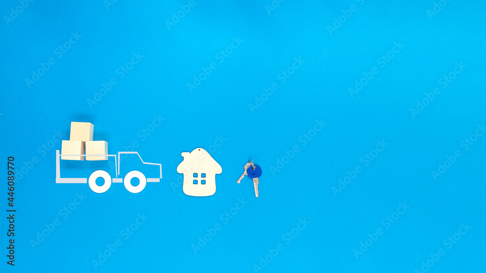 A model of a wooden house, keys and a car on a blue background. A model of a wooden house, keys and a car on a blue background.