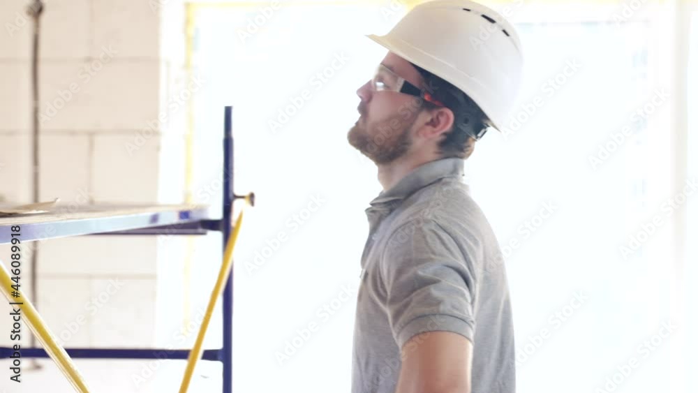 A construction worker in a helmet puts on safety glasses. A construction worker in a helmet puts on safety glasses.