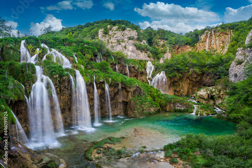 Plitvice, Croatia - Beautiful waterfalls of Plitvice Lakes (Plitvička jezera) in Plitvice National Park on a bright summer day with blue sky and clouds and green foliage and turquise water photo