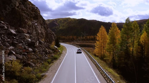 Small white family hatchback moving through picturesque landscapecar driving along the coastal road above dramatic rocky shore towards volcanic mountains. photo
