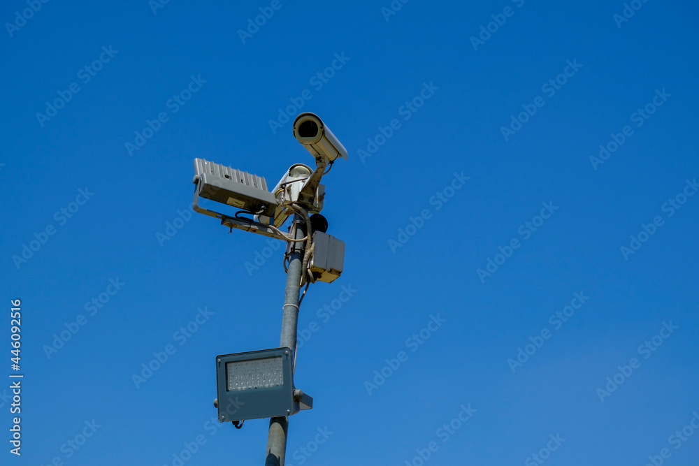 cctv security camera close-up with a lamp on sun battery across blue sky . Security system cctv security camera close-up with a lamp on sun battery across blue sky . Security system