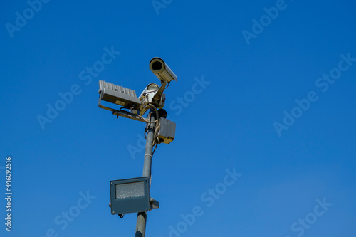 cctv security camera close-up with a lamp on sun battery across blue sky . Security system