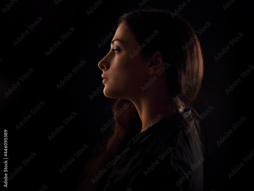Beautiful serious concentration intelligence business woman in darkness with thinking look in the future on black background. portrait in dark shadow low key. Art. Profile