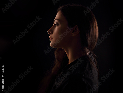 Beautiful serious concentration intelligence business woman in darkness with thinking look in the future on black background. portrait in dark shadow low key. Art. Profile