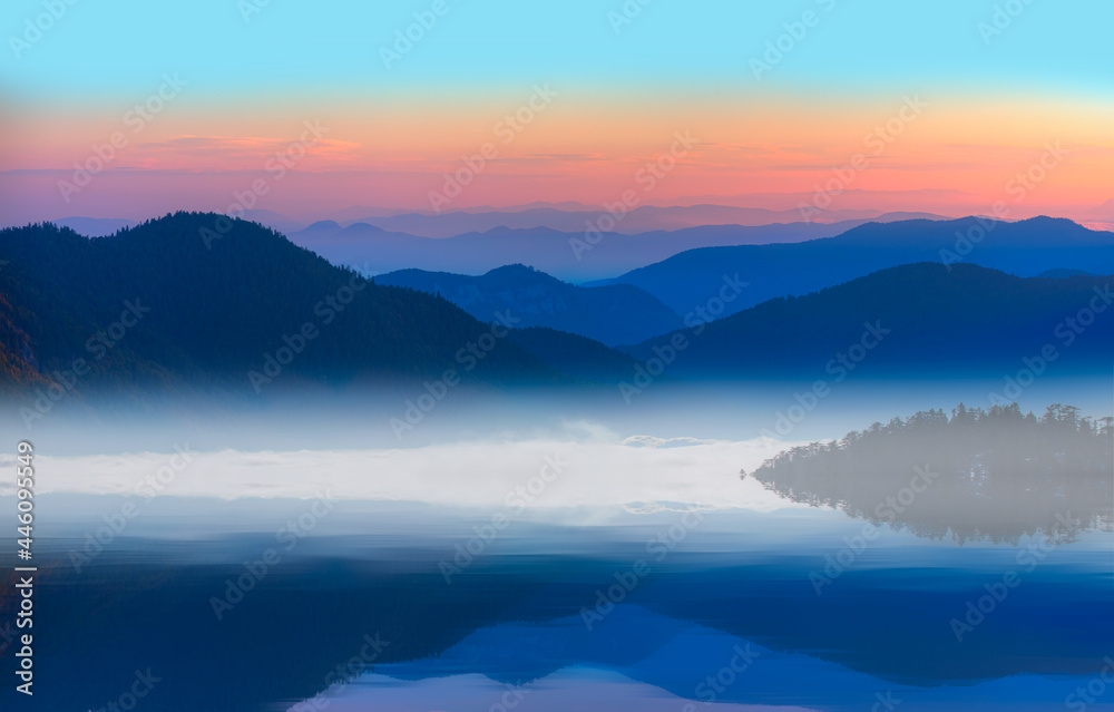Beautiful landscape with high blue mountains with illuminated peaks, and  mountain lake reflection
