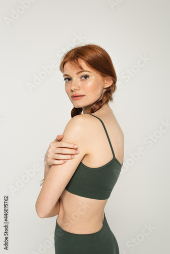 Pretty sportswoman with freckles standing isolated on grey