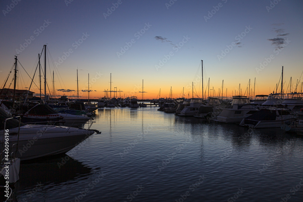Image of yachts in marina after sunset with water reflections