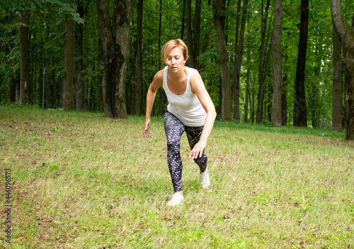 Beautiful young woman goes in for sports in the park in nature. The woman is engaged in fitness in sportswear.