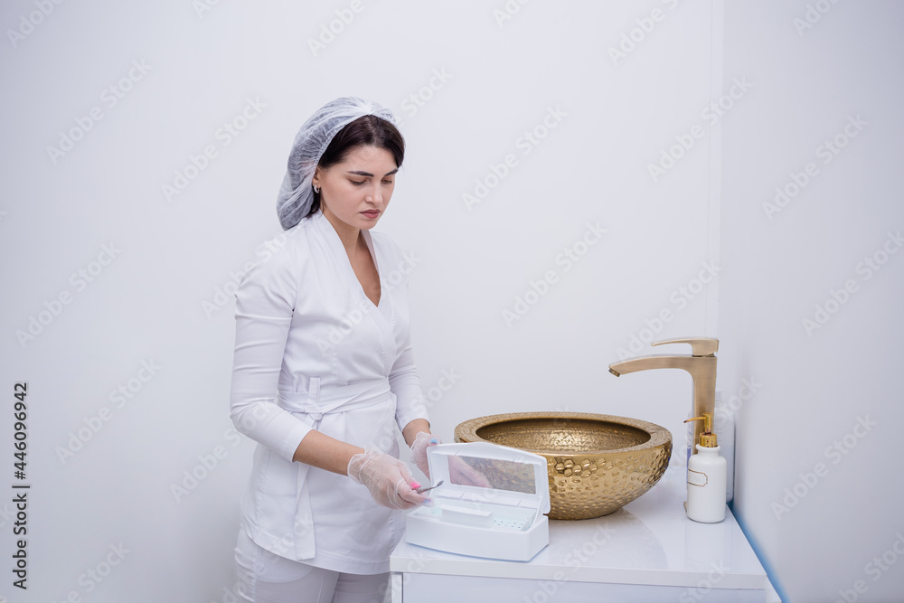 beautician in a white uniform sterilizes instruments in the office beautician in a white uniform sterilizes instruments in the office