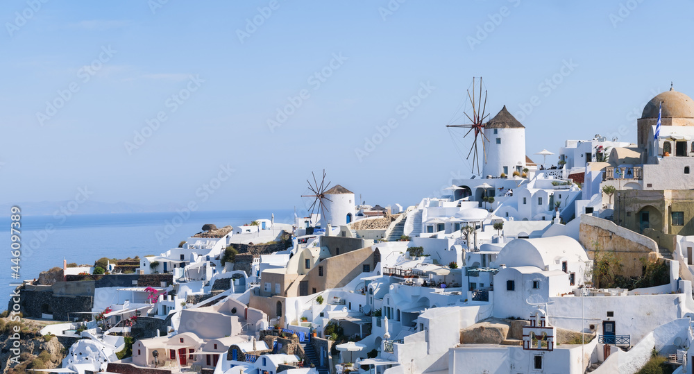 Fototapeta premium Oia village, Santorini, Greece. View of traditional houses in Santorini. Small narrow streets and rooftops of houses, churches and hotels. Landscape at the day time. Travel and vacation photography.