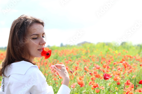 A beautiful girl in a white shirt posing in a poppy field.