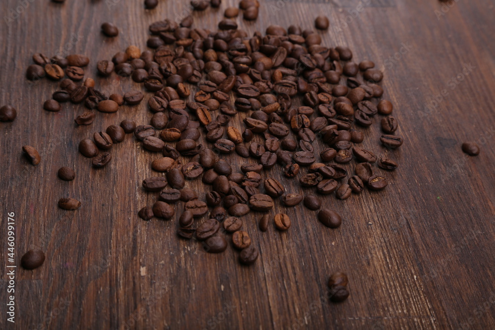 Black coffee grains lie on a brown wooden table, background image Black coffee grains lie on a brown wooden table, background image