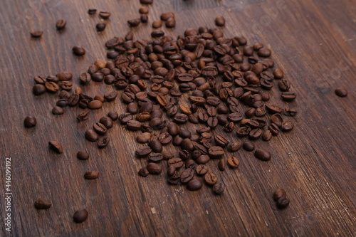 Black coffee grains lie on a brown wooden table, background image