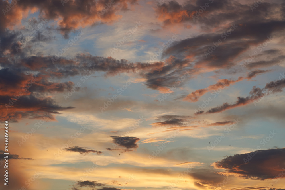 Beautiful evening blue sky at sunset with flaming bright light clouds. A warm summer evening at sunset. Bright sunset. Beautiful evening blue sky at sunset with flaming bright light clouds. A warm summer evening at sunset. Bright sunset.