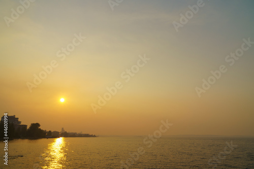 Smog from forest fires enveloped lake coast of city in summer day © Sergei Gorin