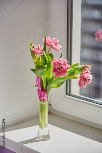 Delicate pink tulips in a vase on the windowsill.