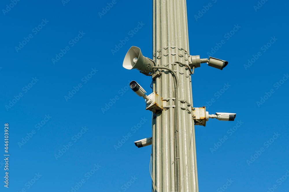 CCTV security cameras and outdoor loudspeaker on clear blue sky background