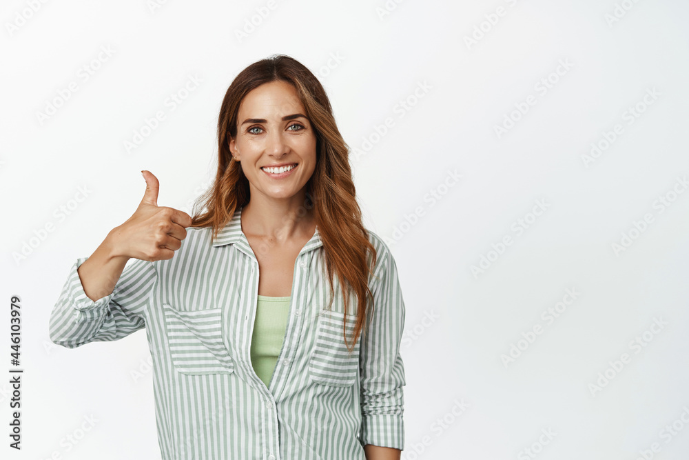 Good work. Smiling adult woman shows thumb up in approval, praise nice job, great choice, looking pleased, standing satisfied against white background Good work. Smiling adult woman shows thumb up in approval, praise nice job, great choice, looking pleased, standing satisfied against white background