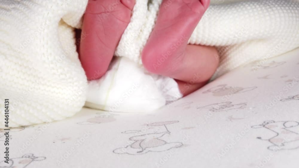 Close up shot of newborn baby in diaper lying on back and jerking her small legs Close up shot of newborn baby in diaper lying on back and jerking her small legs