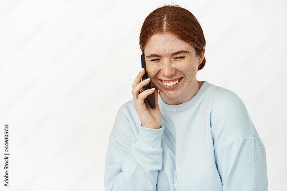 Carefree young woman laughing over phone call, talking on smartphone. Redhead girl chuckle and smile during cellphone chat, happy conversation, white background Carefree young woman laughing over phone call, talking on smartphone. Redhead girl chuckle and smile during cellphone chat, happy conversation, white background