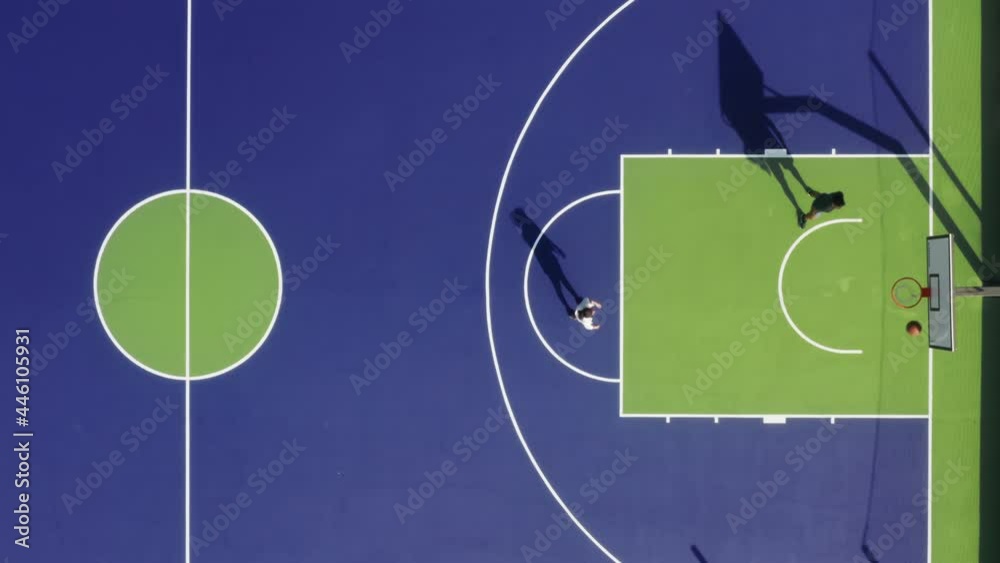 Two men play on a colorful court as seen from top Two men play on a colorful court as seen from top