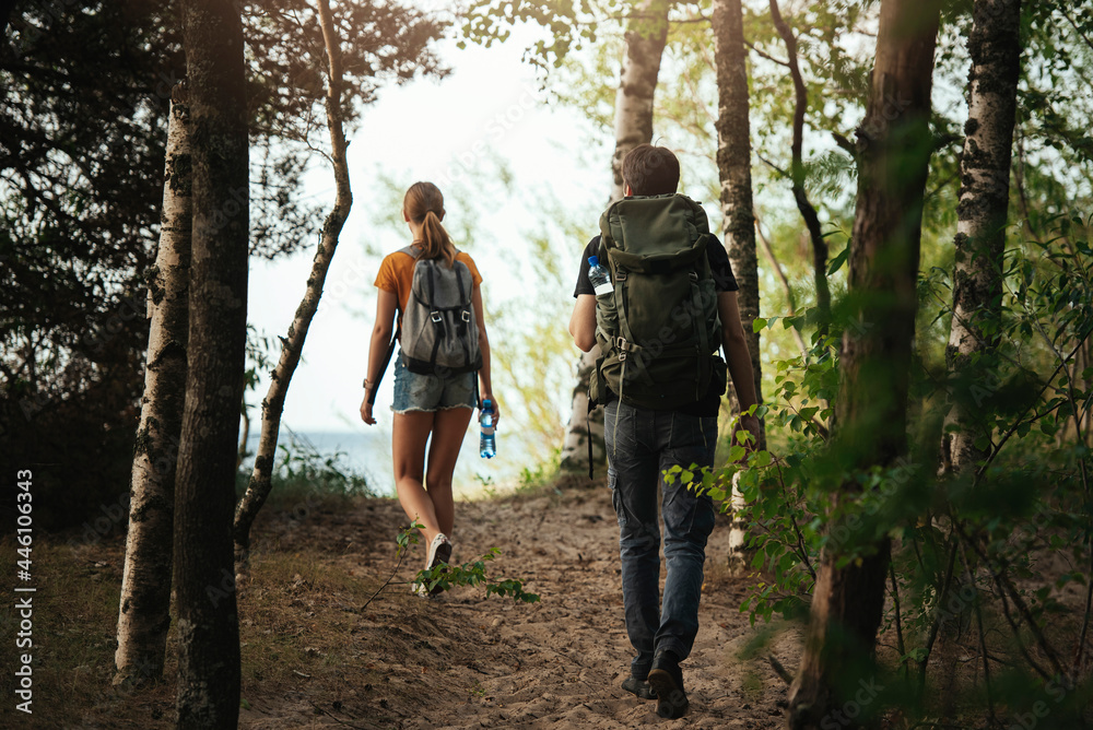 Male and female couple going outdoors backpacking, captured from behind