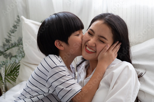 Son kissing mom on white bed in bedroom, Happiness of Asian family relationship concept