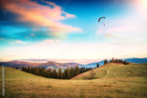 Paraglider over the mountain valley at early morning