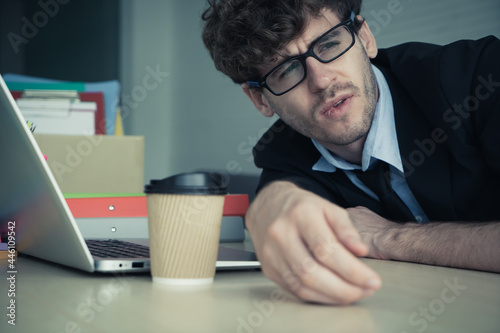 Hopeless business man resting on the office desk with frustation emotion and exhausted face. photo