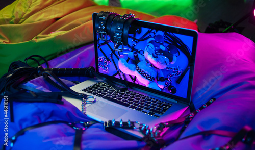 Foto A set of BDSM toys for sex on a laptop on a bright neon background