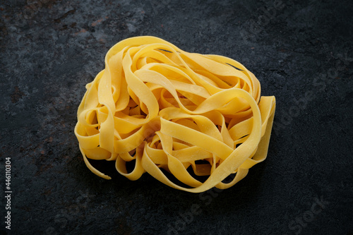 Natural Raw pasta fettuccine on a black stone background. Fresh uncooked egg Italian pasta, close up