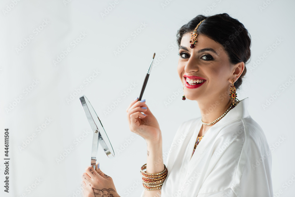 happy indian bride with mehndi holding mirror and cosmetic brush on white happy indian bride with mehndi holding mirror and cosmetic brush on white