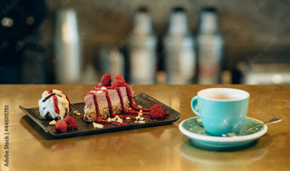 A Slice of Raspberry Cake and Cup of Espresso Coffee on Golden Bar Counter