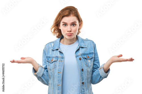 Unsure of bewilderment, the red-haired student shrugs, makes a questioning gesture, confused. Woman on a white isolated background makes a helpless gesture. What's the difference?