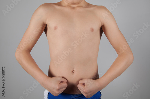 Strong boy with a fist. Gray background.