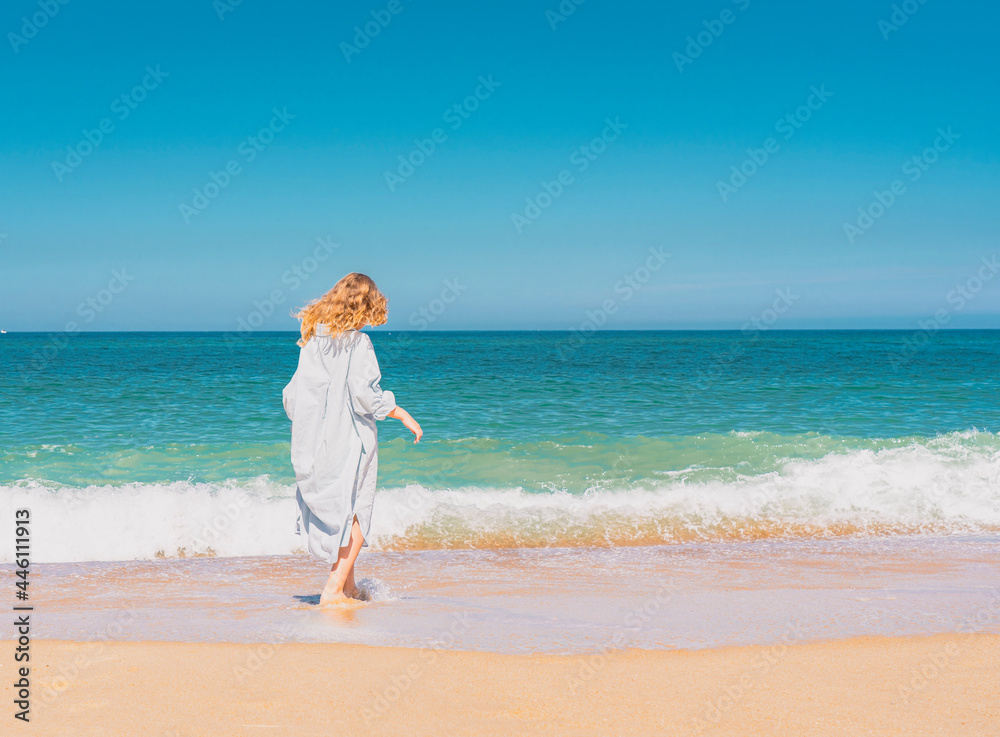 Young beautiful girl in blue dress running on the the sandy beach near the waves. High quality photo Young beautiful girl in blue dress running on the the sandy beach near the waves. High quality photo