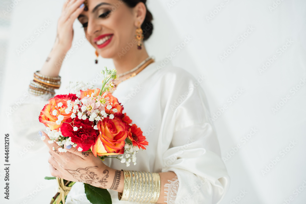 young blurred indian bride with mehndi smiling while holding bouquet of flowers on white young blurred indian bride with mehndi smiling while holding bouquet of flowers on white