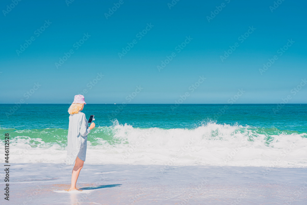Young woman with hat standing near the sea and making selfie. Sea and sky background. Vacation and traveling concept. High quality photo Young woman with hat standing near the sea and making selfie. Sea and sky background. Vacation and traveling concept. High quality photo