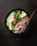 Vietnamese soup Pho Bo with beef and noodles on a dark background, view from above