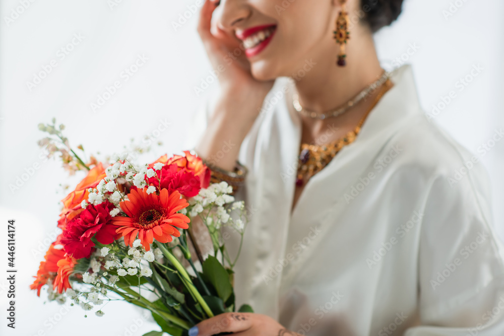 cropped view of cheerful indian bride holding bouquet of flowers on white cropped view of cheerful indian bride holding bouquet of flowers on white