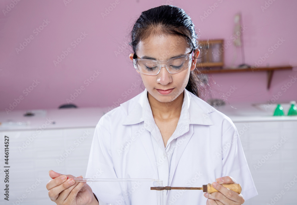 Female Student performing experiment in Chemistry lab with Safety glass wear Female Student performing experiment in Chemistry lab with Safety glass wear